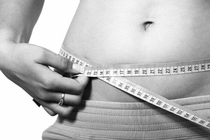 Measuring waist size with a tape measure to track fitness progress