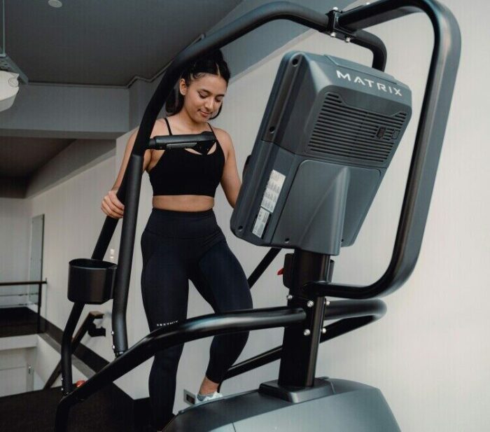 Woman running on an elliptical machine to burn fat at the gym
