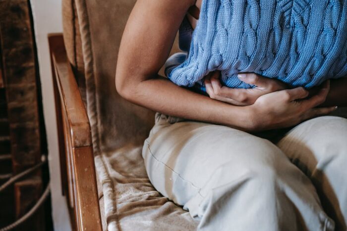 An image of an elderly person holding their stomach in pain