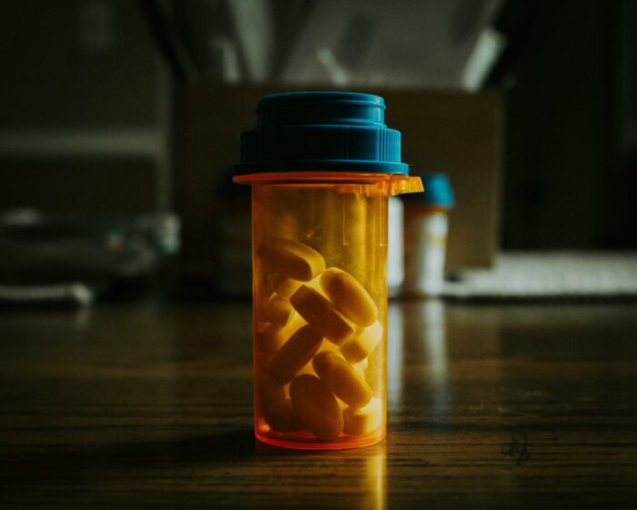 An image of a person holding a pill bottle, symbolizing pharmacological interventions in IBD pain management