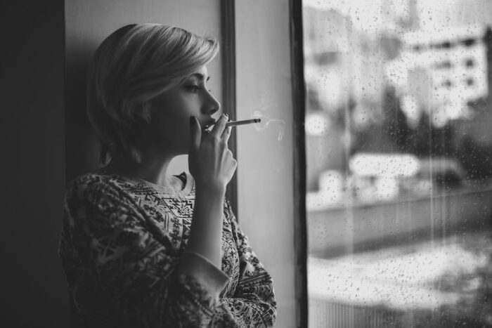 An image of a person holding a cigarette and having a red cross over it, representing the negative impact of smoking on IBD.